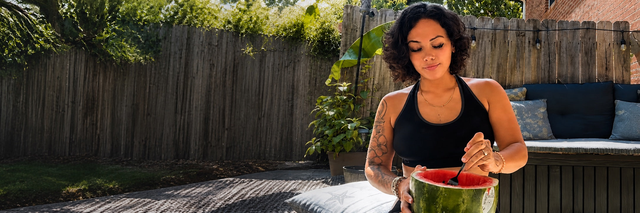 Lauren Allen enjoying watermelon outdoors in a leafy garden